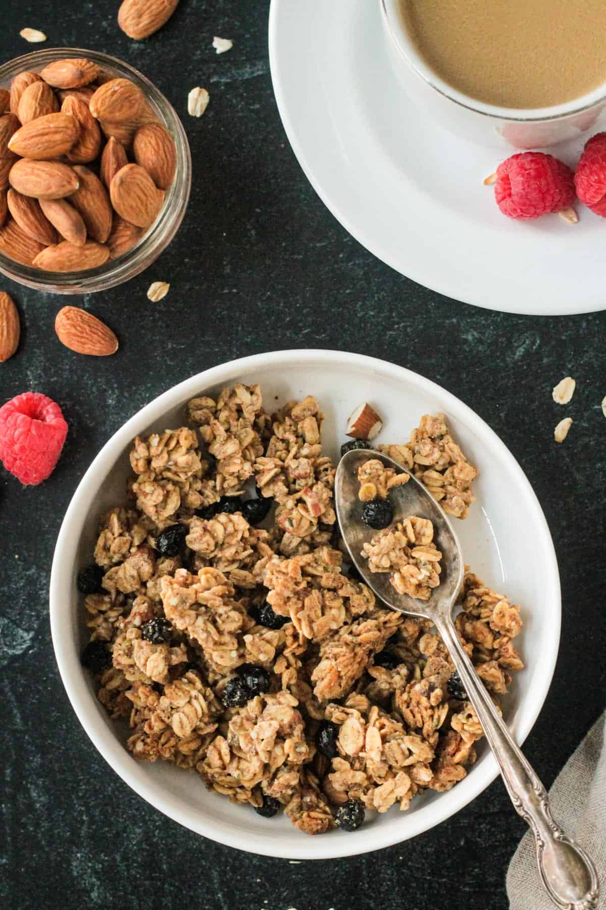 Almond granola in a white bowl with a spoon.