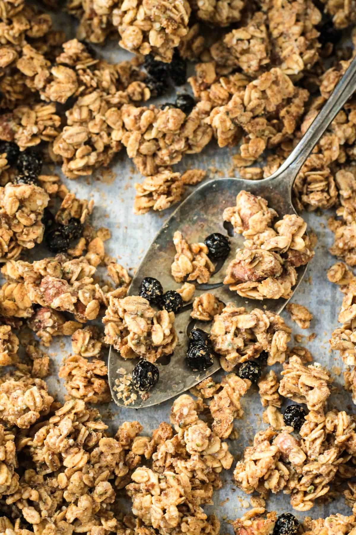 Clusters of granola on a spatula on a parchment lined pan.