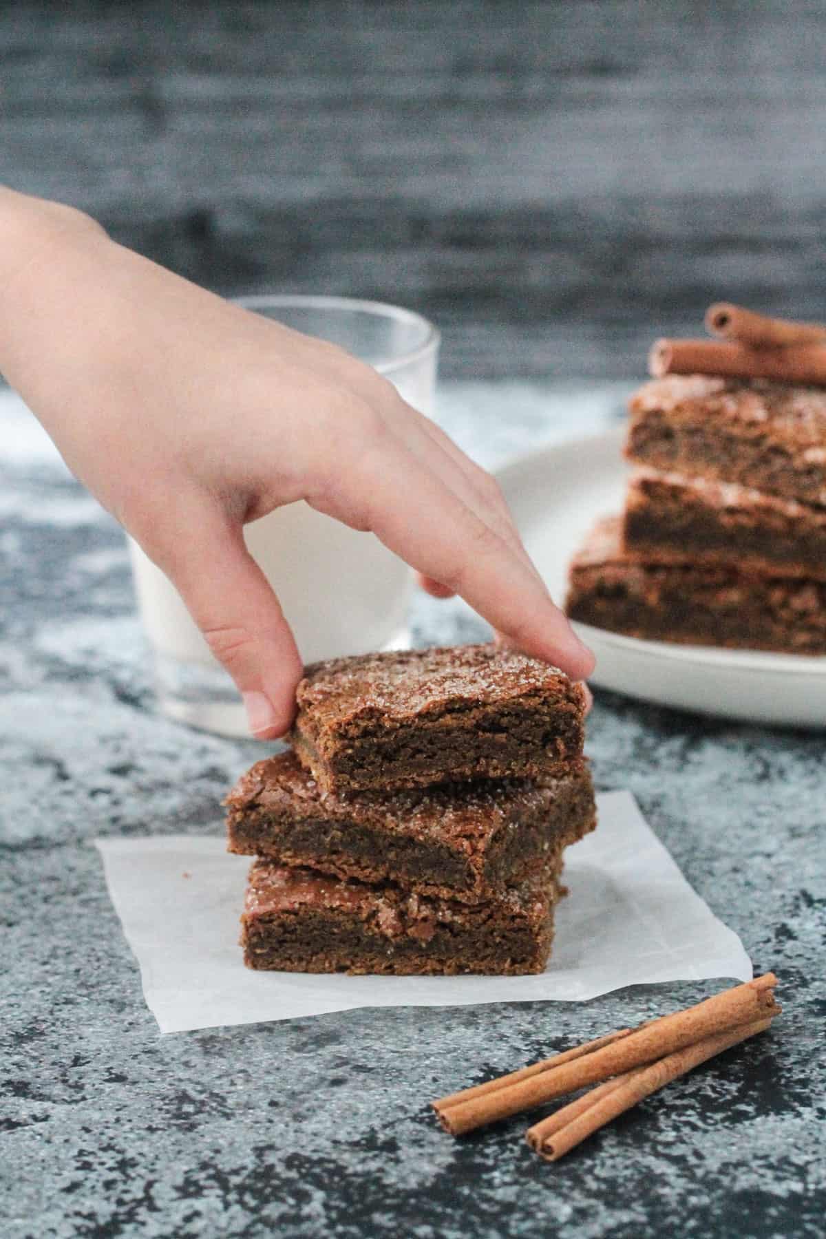 Child's hand grabbing a dessert bar from a stack of 3.