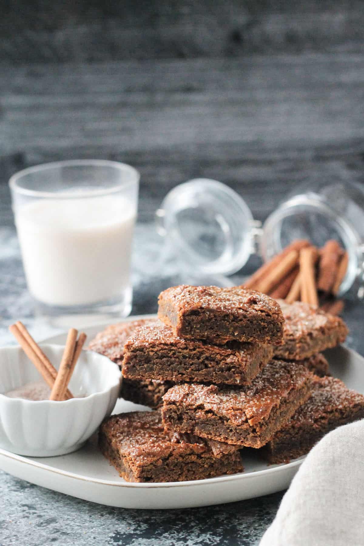 Pile of chickpea blondies on a plate next to a glass of milk. 