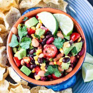Three bean corn salsa in a bowl surrounded by tortilla chips.