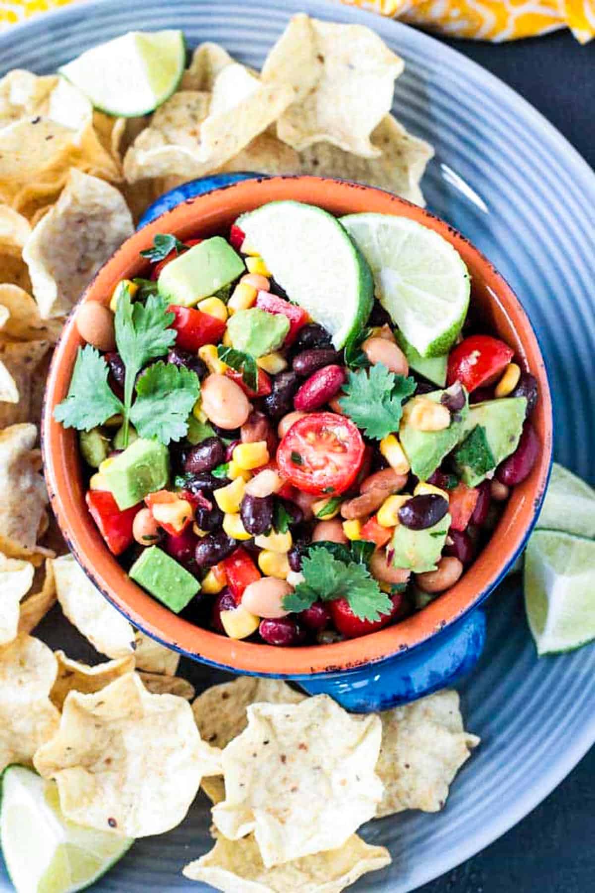 Three bean corn salsa in a bowl surrounded by tortilla chips.