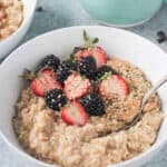 Spoon in a bowl of creamy oats with fresh berries and hemp seeds.