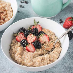 Spoon in a bowl of creamy oats with fresh berries and hemp seeds.