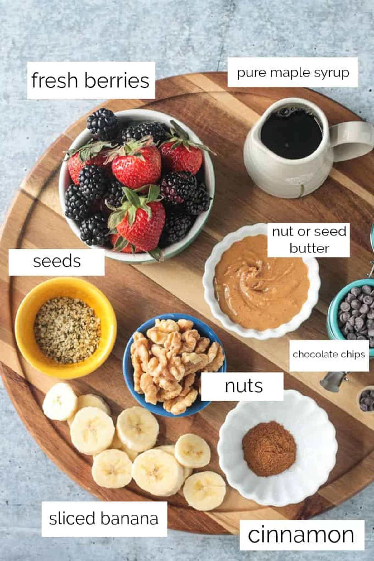 Topping ingredients arrayed in individual bowls on a wooden serving tray.