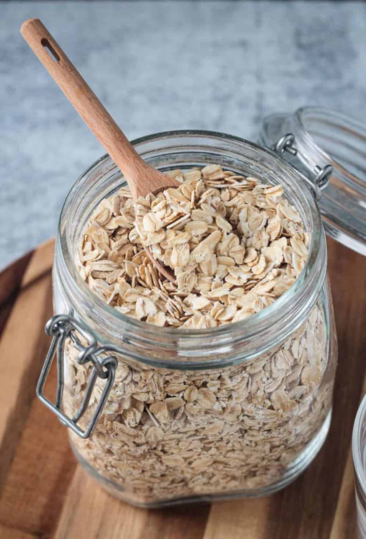 Raw rolled oats in an open glass jar with a wooden spoon.