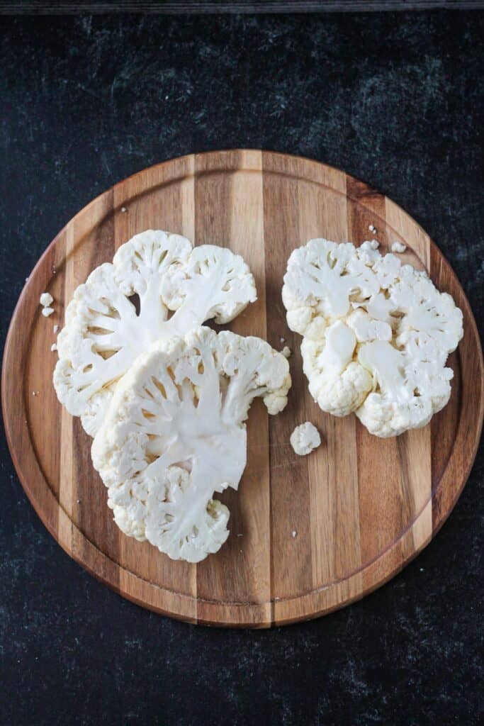 Cauliflower cut into slices on a cutting board.