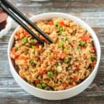 Chopsticks in a bowl of vegan fried rice.