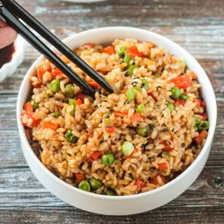 Chopsticks in a bowl of vegan fried rice.