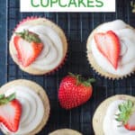 Frosted cupcakes topped with a halved fresh strawberry.