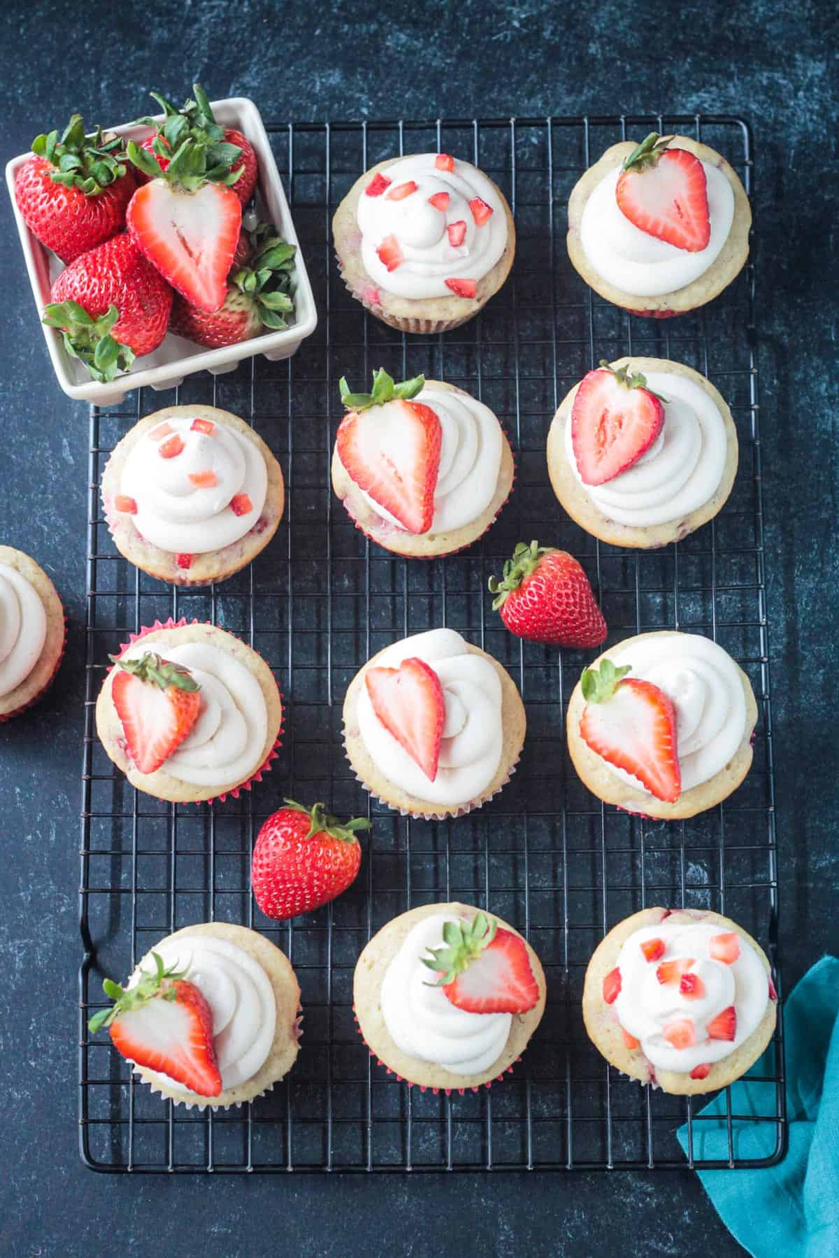 Frosted cupcakes topped with a halved fresh strawberry.