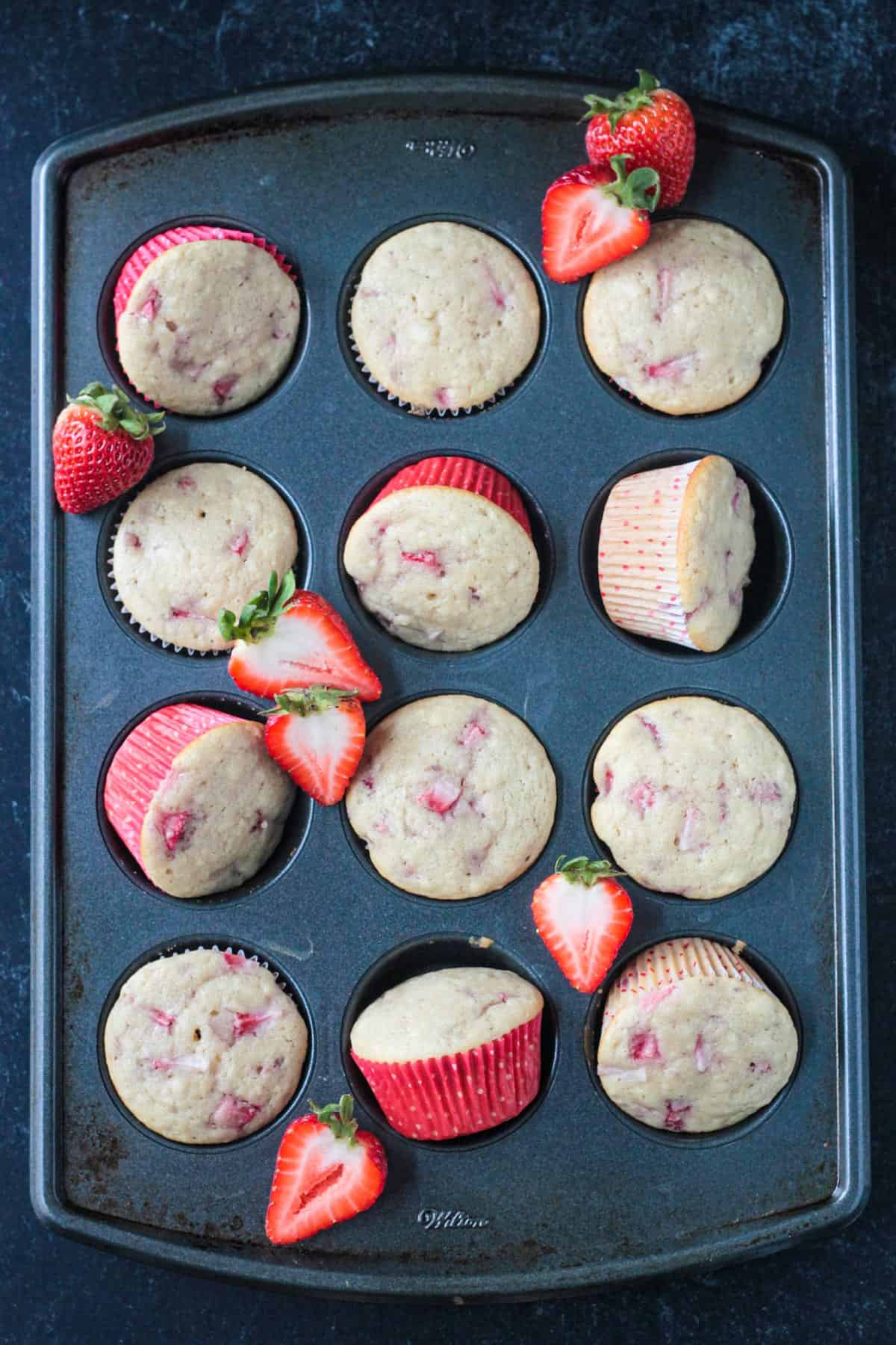 Twelve baked vegan strawberry cupcakes in a cupcake pan.