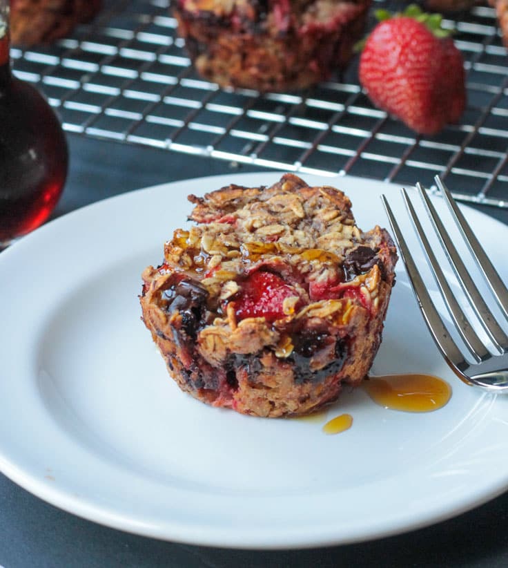 One Strawberry Banana Baked Oatmeal muffin on a white plate with maple syrup dripping down the side.