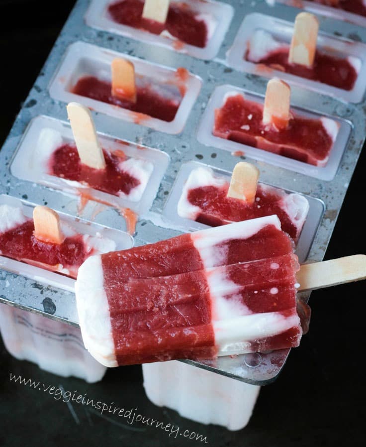 One Strawberry Rhubarb Coconut Milk Popsicle lying on top of a popsicle mold tray holding the remaining popsicles.