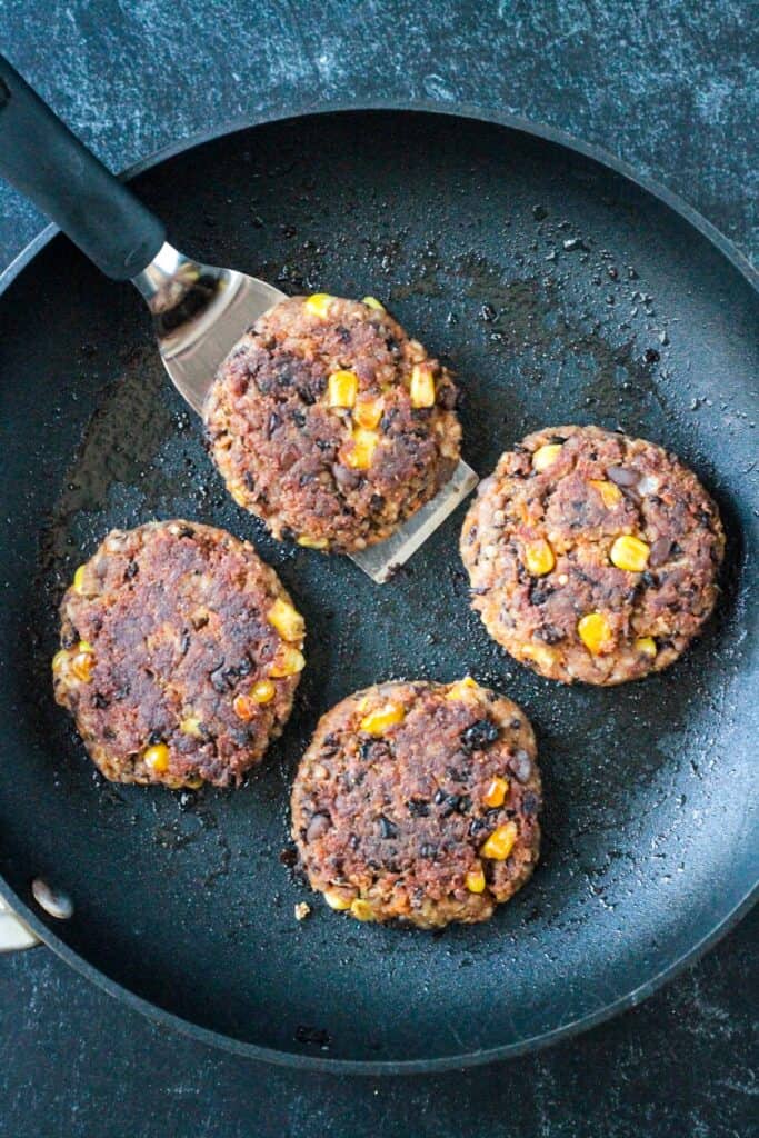 Four patties pan fried in a skillet and ready to serve.
