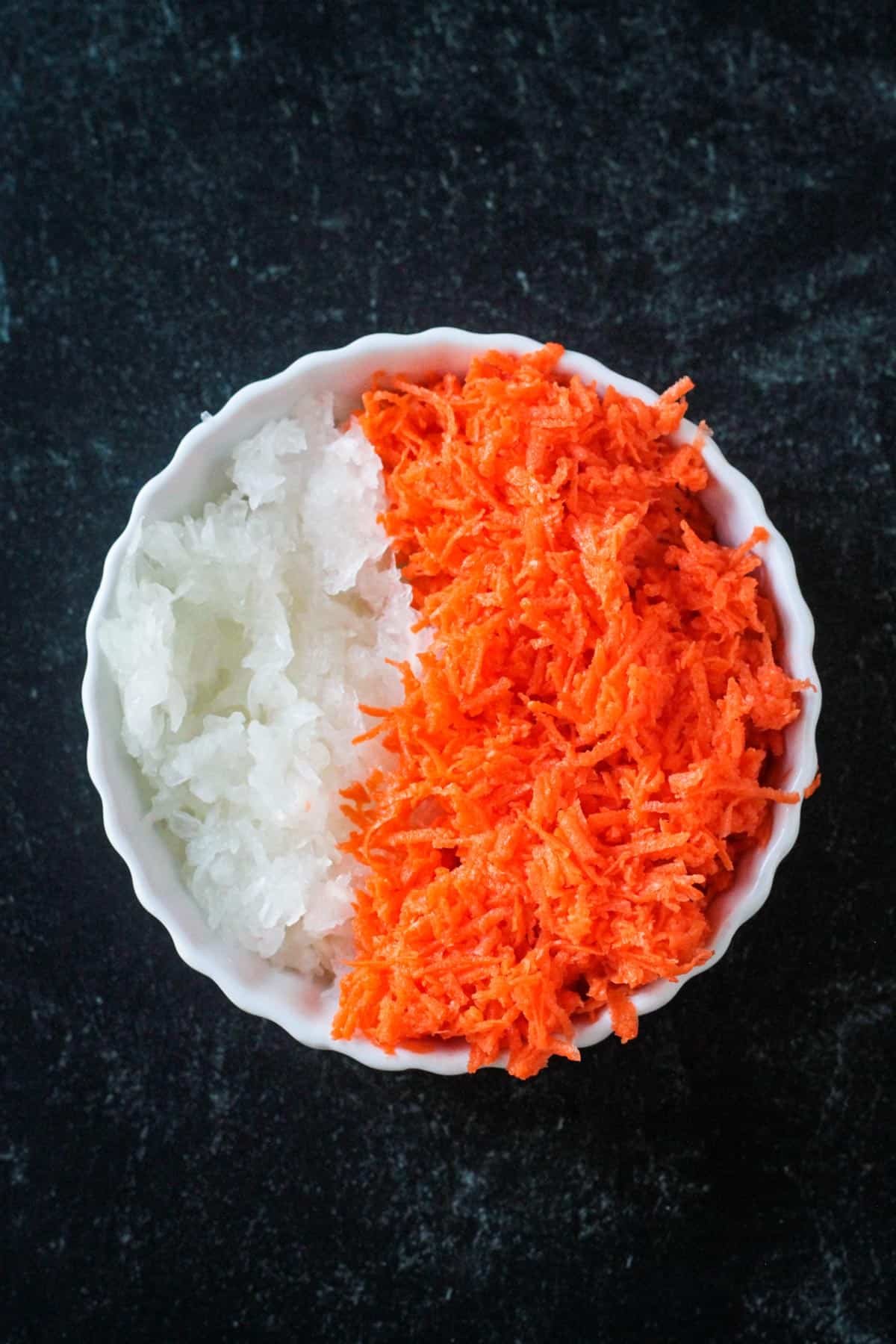 Shredded onions and carrots in a bowl.