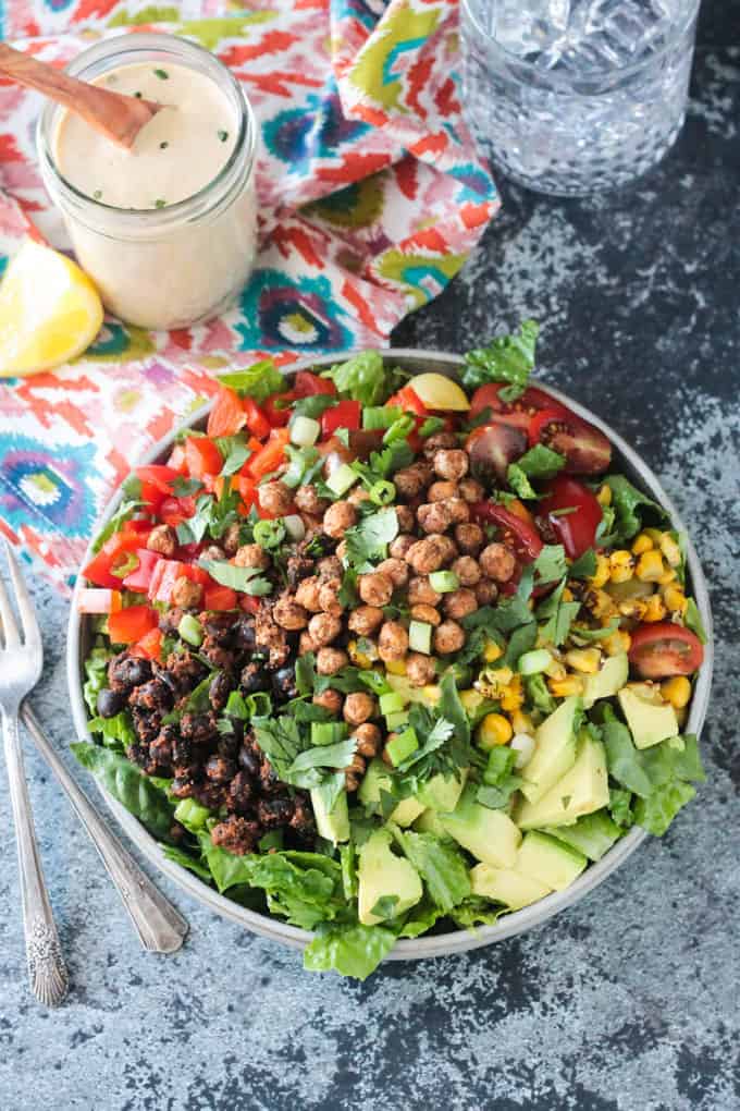 Big plate of salad with avocado, black beans, red peppers,tomatoes, corn, and crunchy roasted chickpeas.