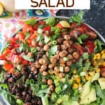 Big plate of healthy taco salad with avocado, black beans, red peppers, tomatoes, corn, and roasted chickpeas.