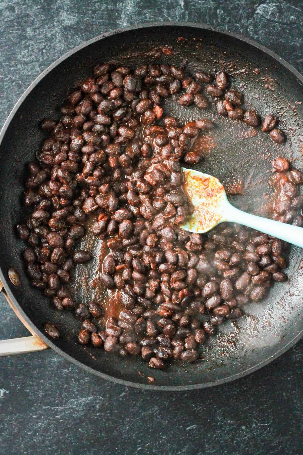 Sautéed seasoned black beans in a skillet.