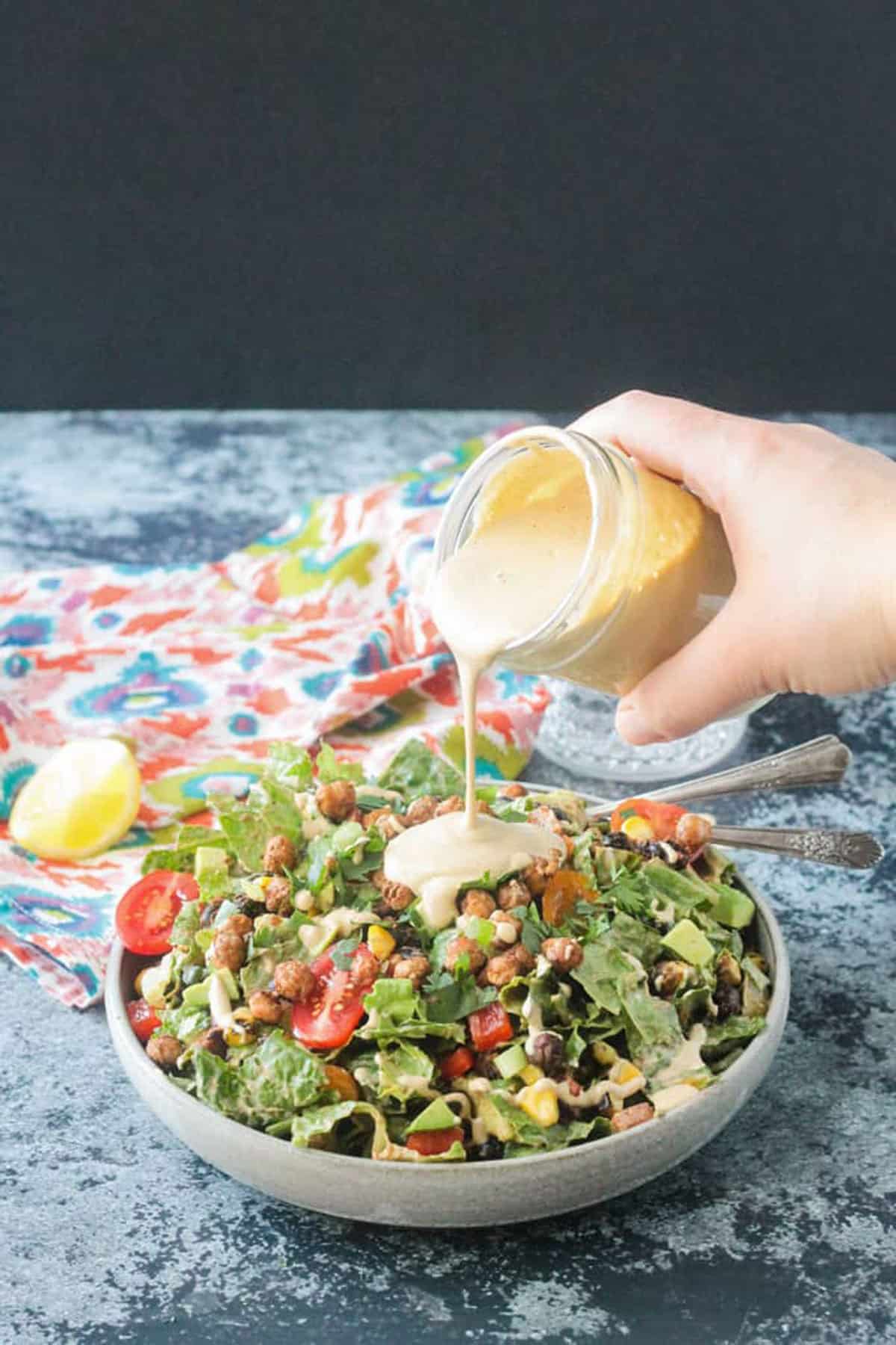 dressing being poured over a taco salad