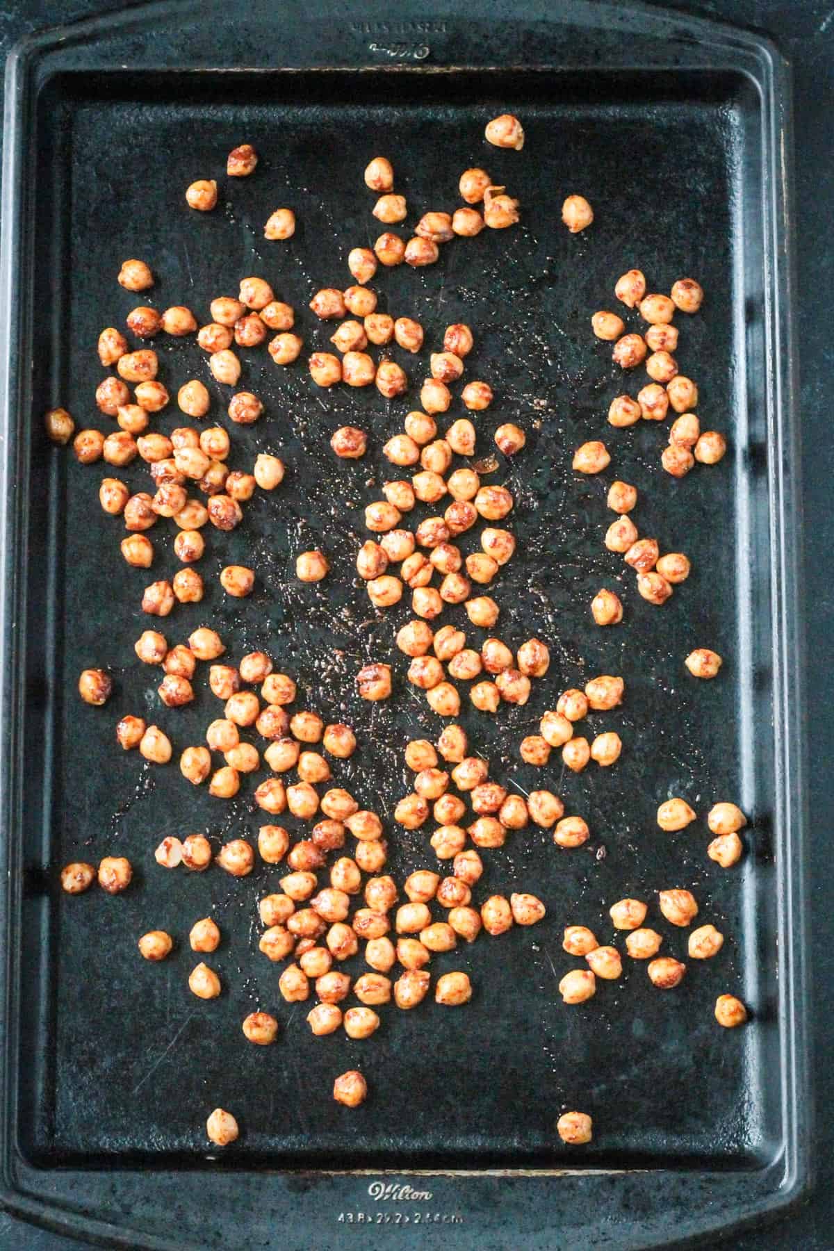 Seasoned chickpeas on a rimmed baking sheet.