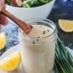 Wooden spoon in a glass jar of vegan ranch dressing.