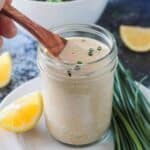 Small wooden spoon in a j ar of vegan ranch dressing.