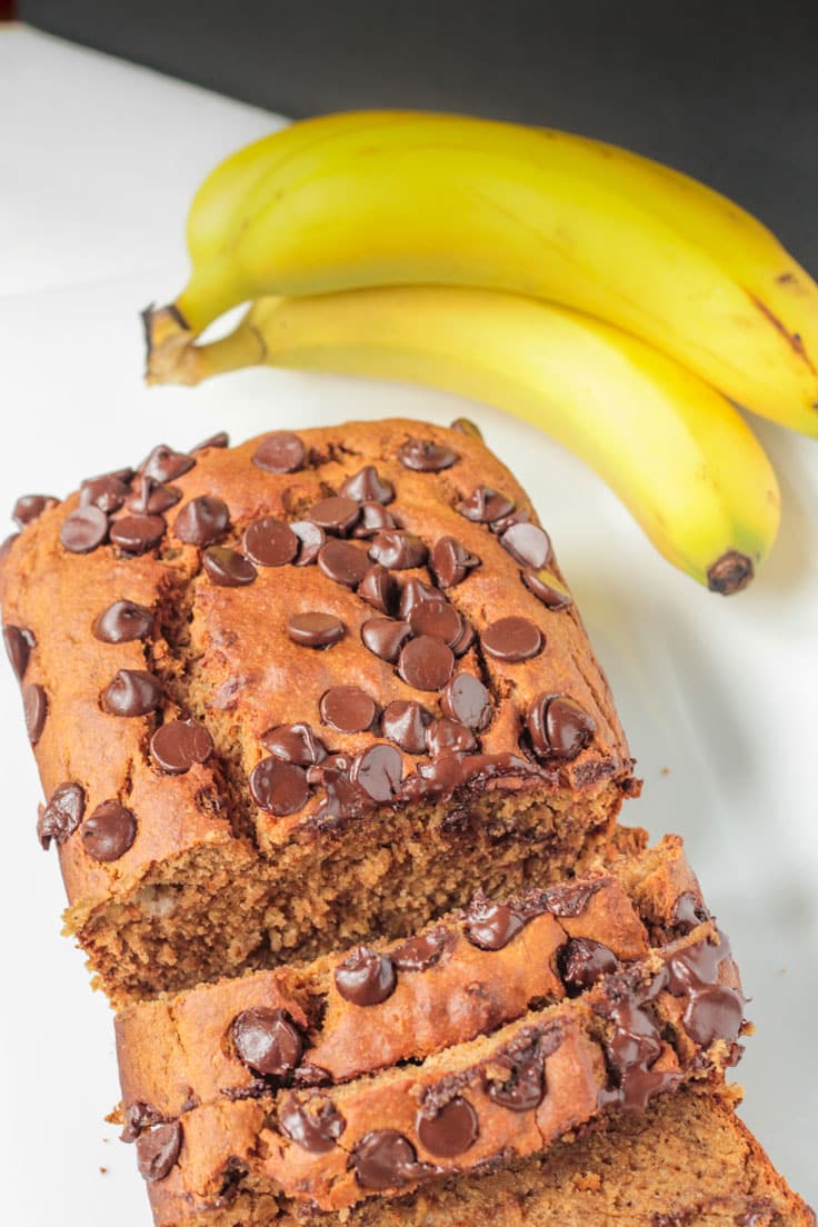 Two bananas behind a loaf of peanut butter banana bread
