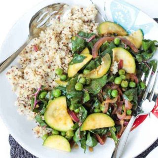 Mixed spring veggies next to quinoa on a plate with utensils.