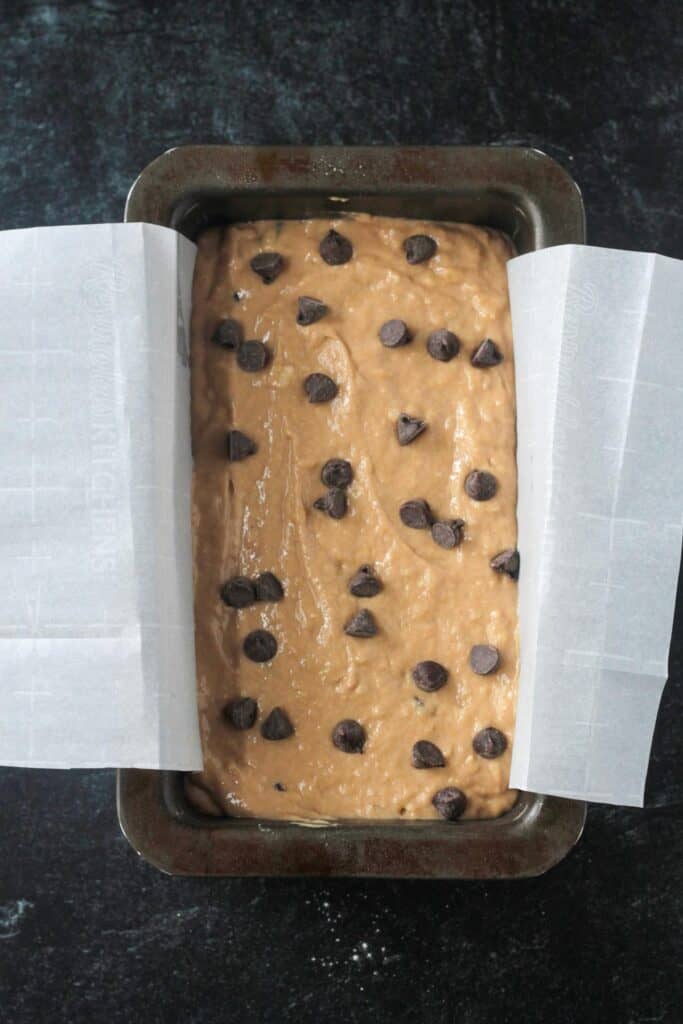 Chocolate chips sprinkled over the top of the batter in a loaf pan.
