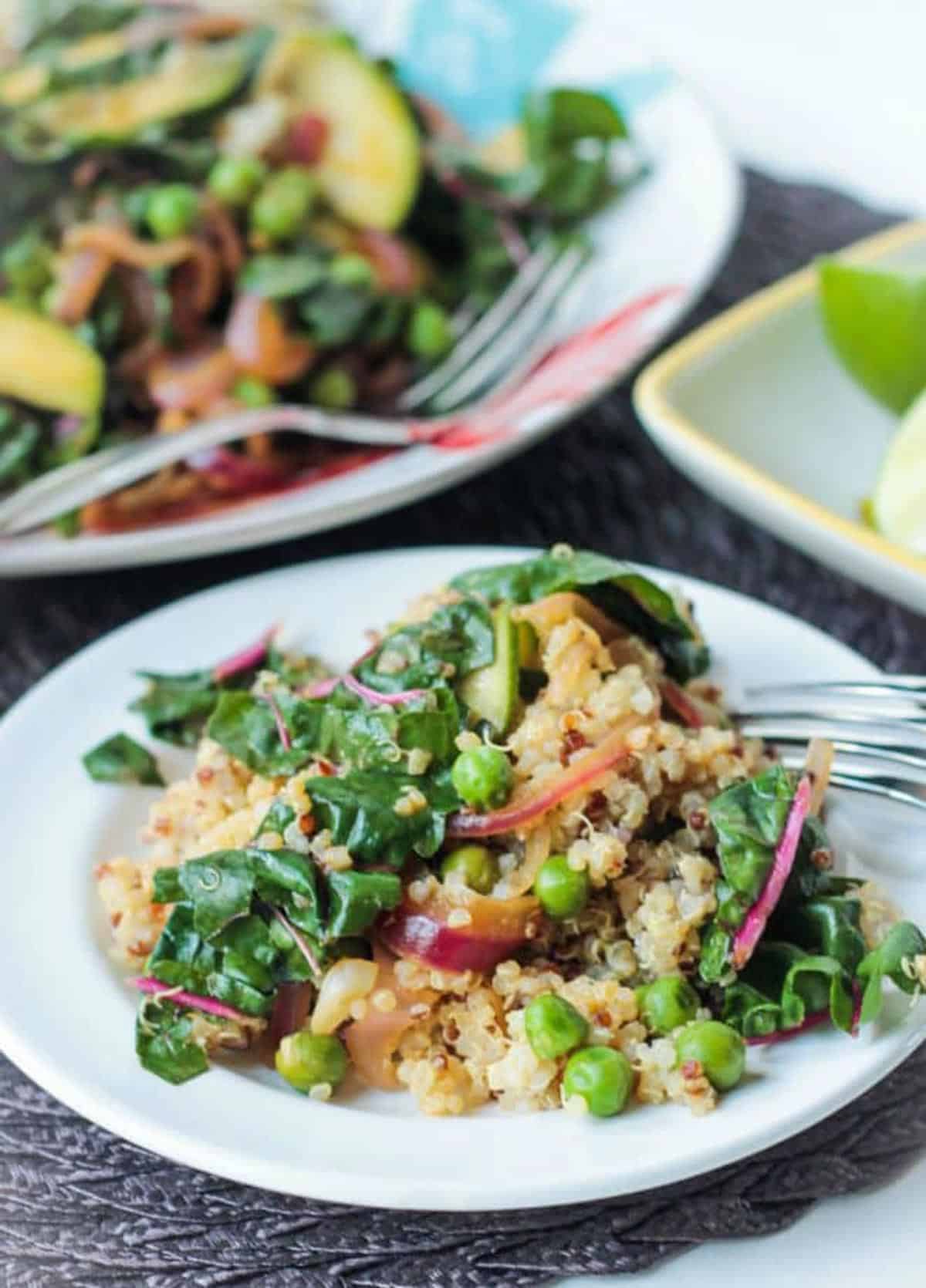 Sautéed chard, peas, zucchini, and onion on top of a cooked white quinoa.