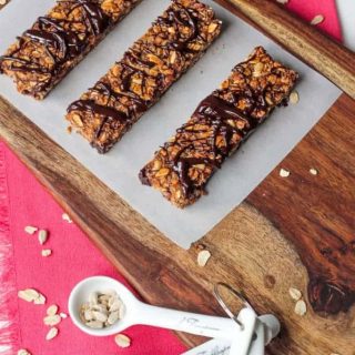 three granola bars drizzled in chocolate on a piece of parchment paper