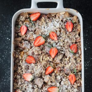 Baked casserole garnished with halved fresh strawberries and a sprinkle of powdered sugar.