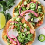 Vegan tostadas with refried beans and lots of toppings on a plate.