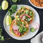 Vegan tostadas with refried beans and lots of toppings on a plate.