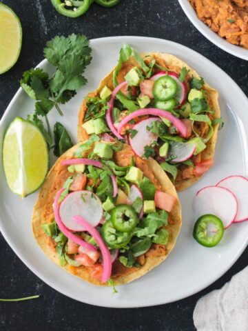 Vegan tostadas with refried beans and lots of toppings on a plate.