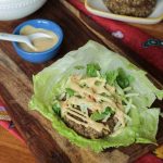 veggie burger in a lettuce leaf with sauce drizzled over the top