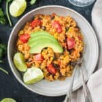 Serving of vegan Mexican risotto topped with sliced avocado on a plate.