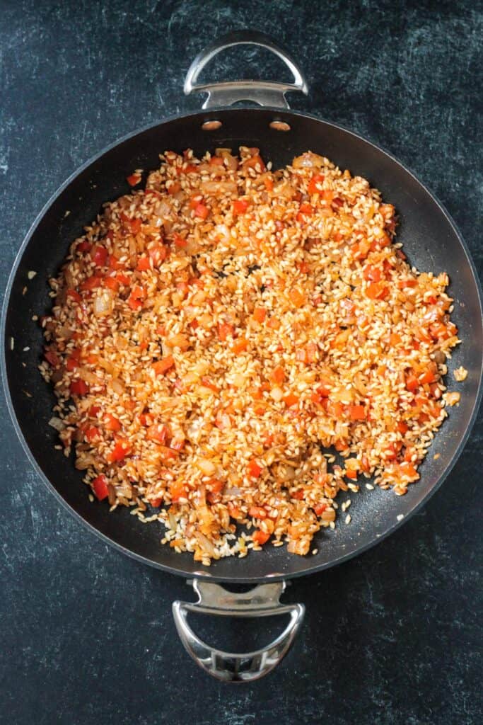 Arborio rice added to the skillet of sautéed veggies.