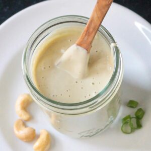 Small wooden spoon in a jar of creamy dressing.