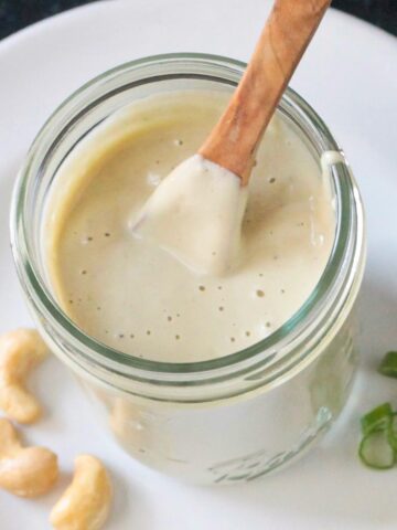 Small wooden spoon in a jar of creamy dressing.