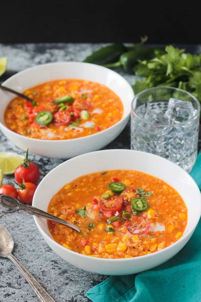 Two bowls of soup with spoons in them.