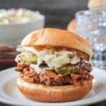 Saucy shredded bbq jackfruit on a bun with creamy coleslaw and pickle slices.