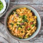 Bowl of vegan chili mac with kidney beans topped with chopped fresh cilantro.