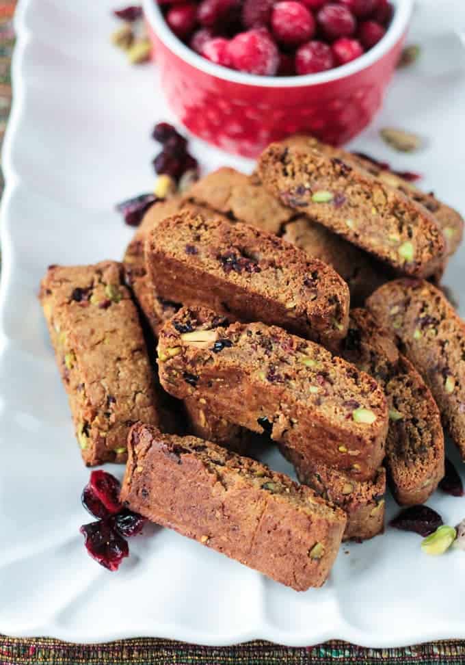 Pile of Whole Wheat Cranberry Pistachio Vegan Biscotti on a white plate.
