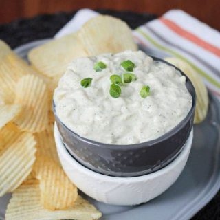 Vegan French Onion Dip in a bowl surrounded by ridged potato chips.