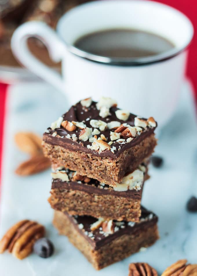 3 Vegan Toffee Bars stacked in front of a cup of coffee.
