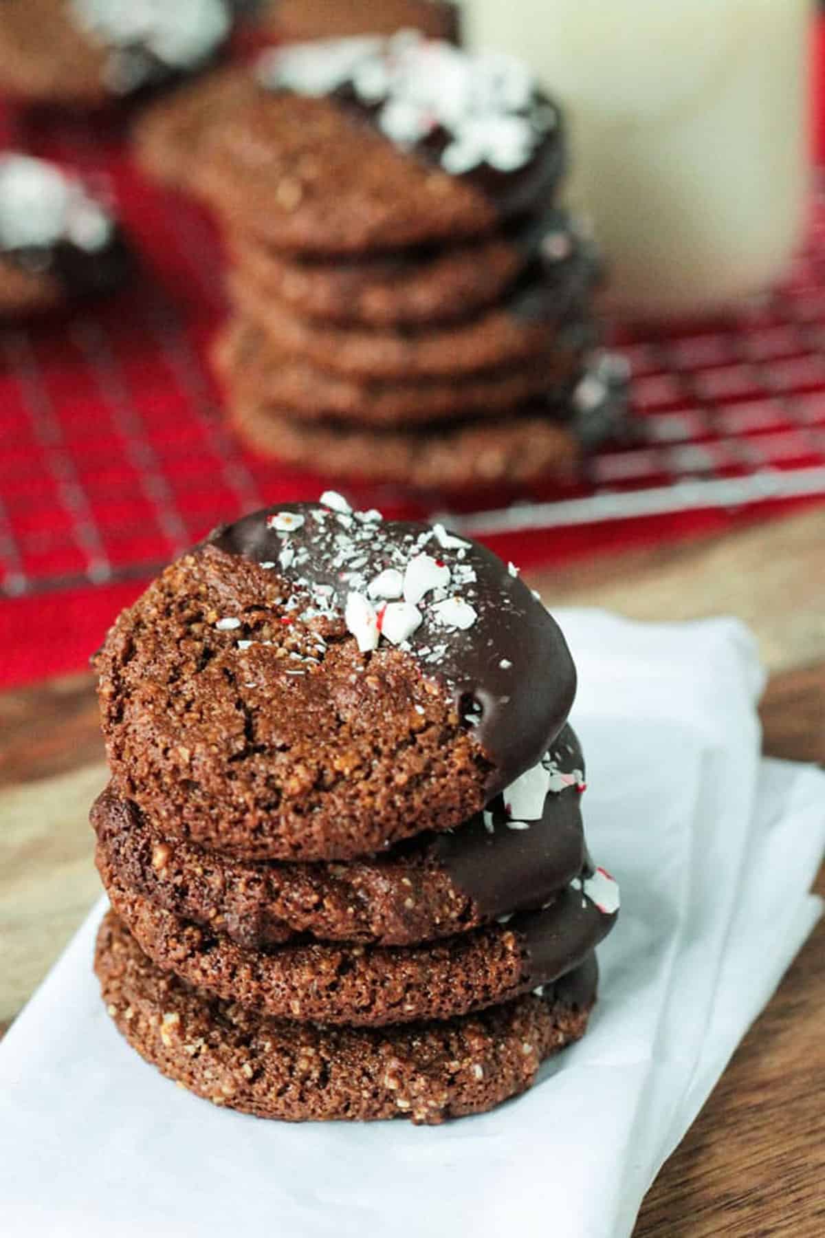 Stack of chocolate molasses cookies partially dipped in chocolate and sprinkled with crushed peppermint candies.