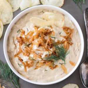 Vegan French Onion Dip in a serving bowl topped with extra caramelized onions and fresh dill.
