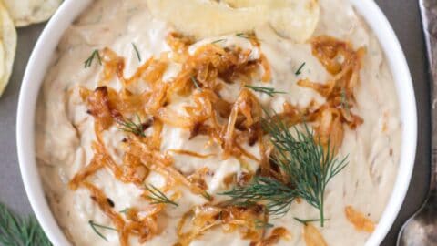 Vegan French Onion Dip in a serving bowl topped with extra caramelized onions and fresh dill.